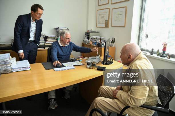 Cardiologist Benny Levenson puts a patient's information onto a card with a card reader, as German Health Minister Karl Lauterbach looks on, during a...