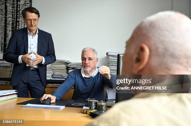 Cardiologist Benny Levenson holds a health card of patient Peter Jordan as German Health Minister Karl Lauterbach looks on, during a presentation of...