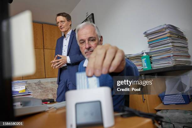 German Health Minister Karl Lauterbach observes as doctor Benny Levenson inserts the health insurance card of 86-year-old Peter Jordan into a...