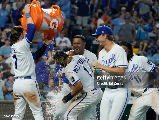 Melendez of the Kansas City Royals is doused with water by Bobby Witt Jr. #7 as he celebrates with teammates after scoring on a walk-off balk in the...