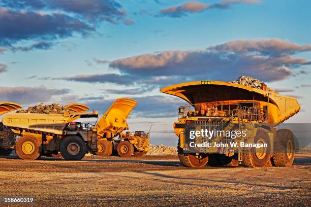 dump trucks dumping rocks at a gold mine - mina de oro fotografías e imágenes de stock