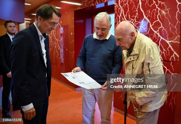 Cardiologist Benny Levenson shows patient Peter Jordan a printed out e-prescription, as German Health Minister Karl Lauterbach looks on, during a...