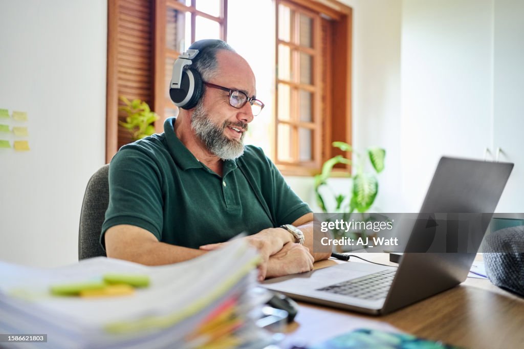 Reifer Mann mit Videoanruf auf Laptop im Homeoffice