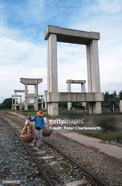 Street vendor walks past stonehenge or the hopeless project. This is how the Thai public now refer to the concrete structures that line the road to...