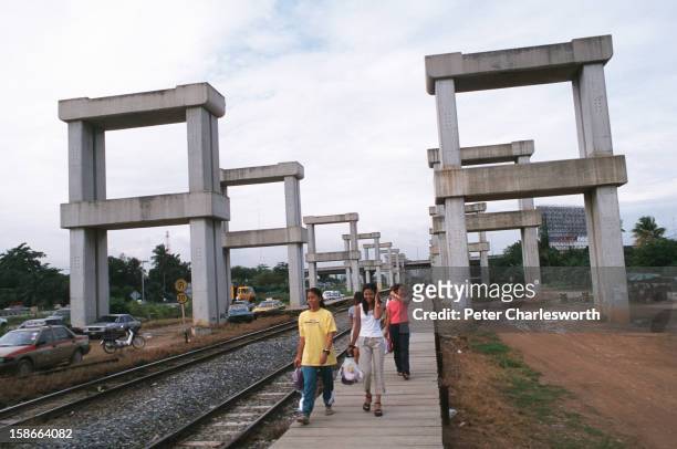 Train passengers walk on a station platform under the shadow of stonehenge or the hopeless project. This is how the Thai public now refer to the...