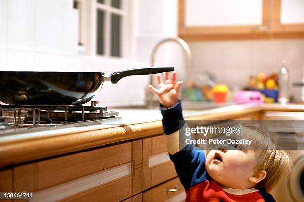 young boy reaching for a hot pan on a hob - accident and emergency uk stock-fotos und bilder