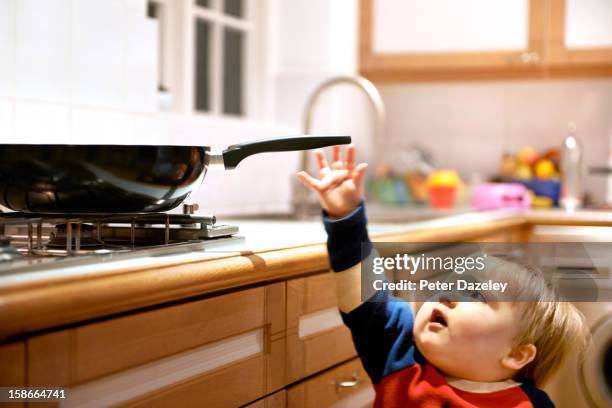 young boy reaching for a hot pan on a hob - accident bénin photos et images de collection