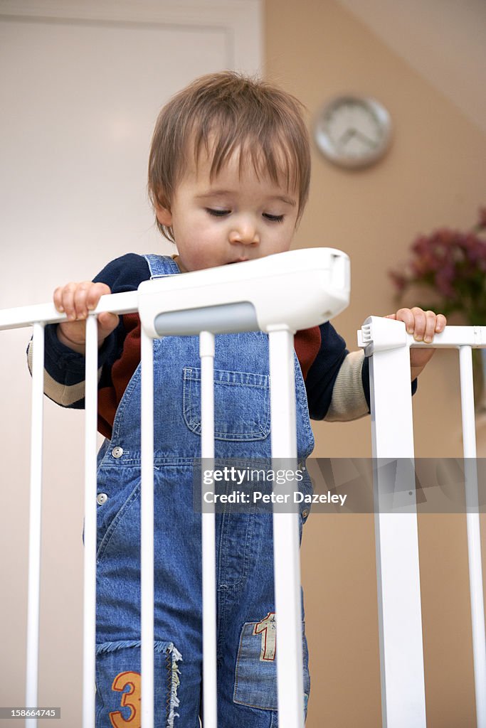 Young boy opening an unlocked stair gate