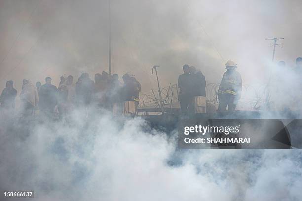 Afghan firefighters and local volunteers salvage goods from shops after a huge fire swept through a market in Kabul on December 23, 2012. A huge fire...