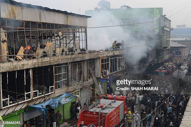 Afghan firefighters and onlookers are pictured at the scene after a huge fire swept through a market in Kabul on December 23, 2012. A huge fire swept...
