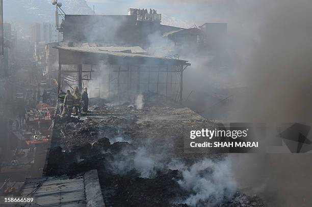 Afghan firefighters and local volunteers salvage goods from shops after a huge fire swept through a market in Kabul on December 23, 2012. A huge fire...