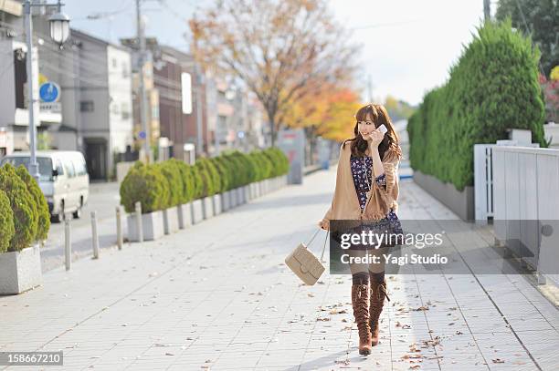 young woman using a smartphone in the city - japanese short skirts stockfoto's en -beelden