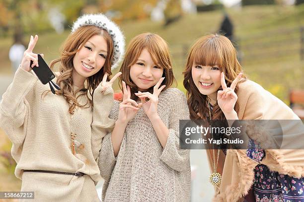 three young women in the park,smiling - ピースサイン ストックフォトと画像