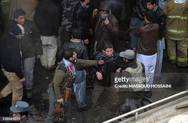 Afghanistan policemen try to move a man from the scene after a huge fire swept through a market in Kabul on December 23, 2012. A huge fire swept...