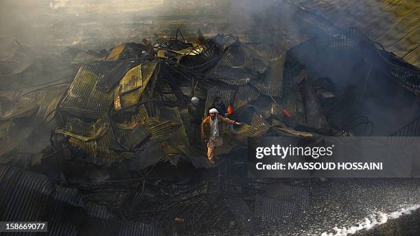 Afghan men guide firefighters after a huge fire swept through a market in Kabul on December 23, 2012. A huge fire swept through a market in downtown...