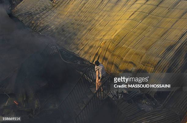 An Afghan man walks through the area of a fire that swept through a market in Kabul on December 23, 2012. A huge fire swept through a market in...