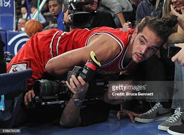 Joakim Noah of the Chicago Bulls lands on a TV camerman during the second quarter against the New York Knicks at Madison Square Garden on December...