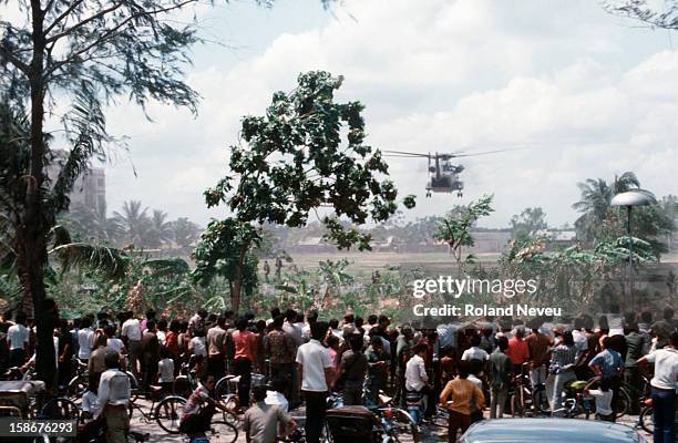 Thousands of Cambodians gather behind a school perimeter fence near the American embassy to witness the final evacuation of US and foreign nationals...