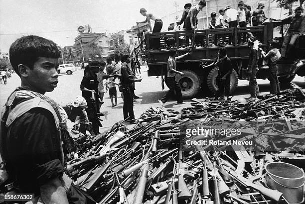 The fall of Phnom Penh. Throughout the day, Khmer Rouge regular forces dressed in black collected weapons left behind by Lon Nol soldiers who had...