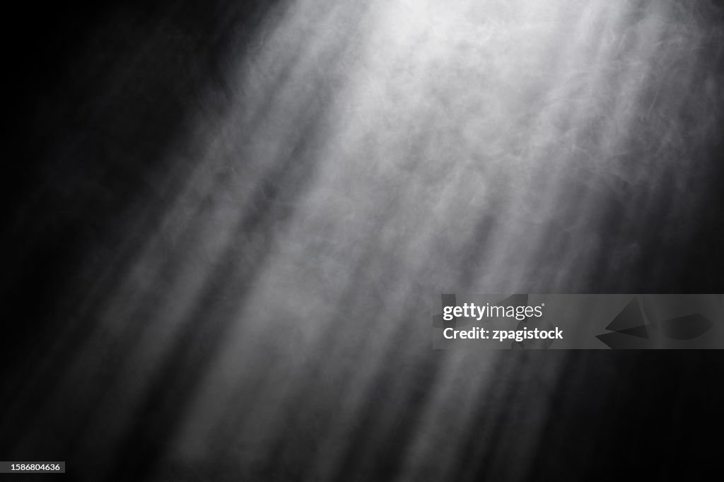 Smoke against black background with light rays and beams