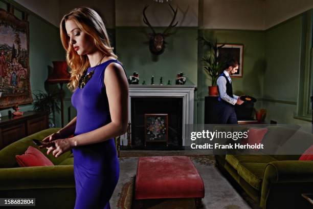 man and woman in livingroom, woman using phone - form fitted dress stock pictures, royalty-free photos & images