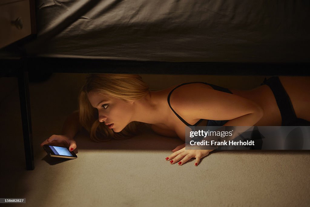 Womanb using phone under bed