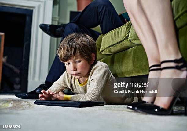 boy using tablet computer under sofa - under sofa stockfoto's en -beelden