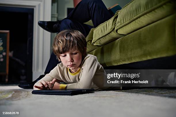 boy on tablet computer under sofa - different emotions children stockfoto's en -beelden