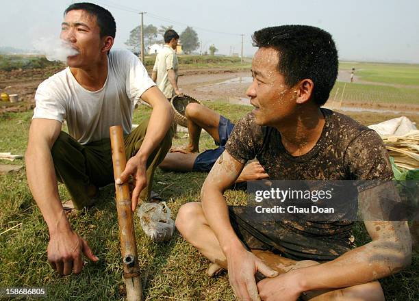 Vietnamese farmers take a break to smoke tobacco after catching fish in their rice fields, on the outskirts of Hanoi. Most of the rice farmers in...