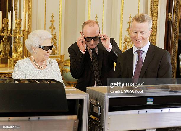 Queen Elizabeth II with producer John McAndrew and director John Bennett watch the recording of her Christmas message to the Commonwealth which is to...
