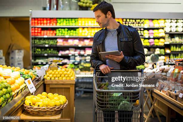 a man using a digital tablet for shopping. - shopping list trolley stock pictures, royalty-free photos & images