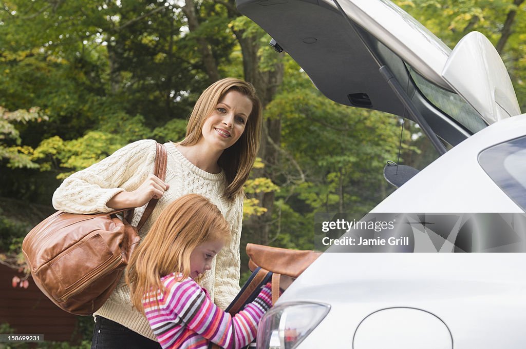 Mother and daughter putting luggage in car