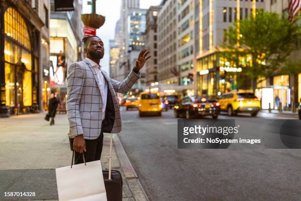 wohlhabender schwarzer geschäftsmann auf einer reise nach nyc, einkaufen, ein taxi rufen - nyc cab stock-fotos und bilder