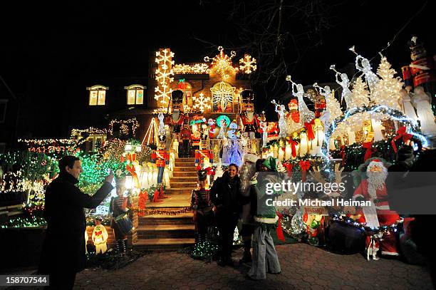 People pose for a photo with a man dressed as Santa Claus in front of a decorated house on Christmas Eve December 24, 2012 in the Dyker Heights...