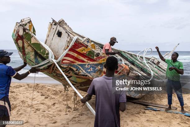 Fishermen attach ropes to a beached pirogue to eventually move it from the beach in Dakar on August 9 in which 17 migrants lost their lives after it...