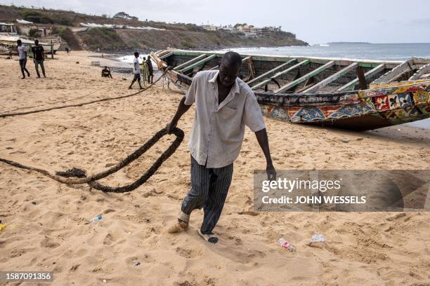 Fisherman pulls a rope as they try to move a beached pirogue in Dakar on August 9 in which 17 migrants lost their lives after it capsized off the...