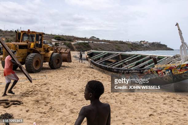 Young boy looks on as a bulldozer tries to move a beached pirogue in Dakar on August 9 in which 17 migrants lost their lives after it capsized off...