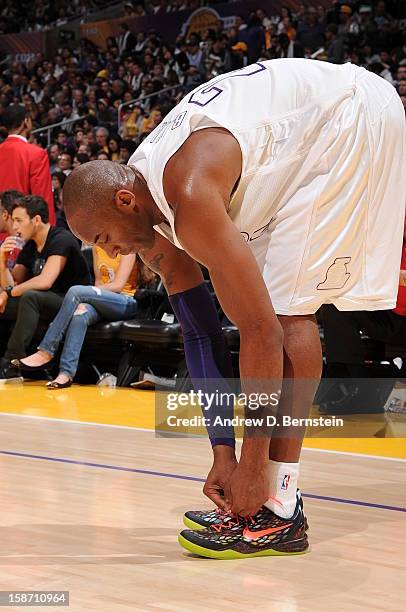 Kobe Bryant of the Los Angeles Lakers ties his shoe during a game against the New York Knicks at Staples Center on December 25, 2012 in Los Angeles,...