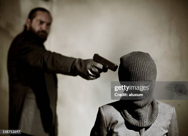 bearded man pointing a gun at a man's temple to execute him - handgun stock pictures, royalty-free photos & images