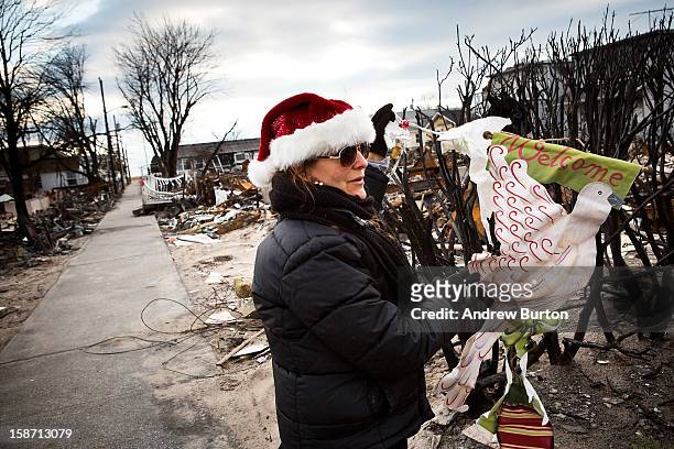 Volunteer who would only identify herself as "Nancy" hangs an ornament on the remains of a dead bush December 25, 2012 in the Breezy Point...