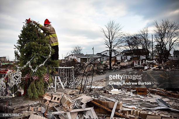 Edward ''Roaddawg'' Manley, a volunteer and honorary firefighter with the Point Breeze Volunteer Fire Department, places a star on top of a Christmas...