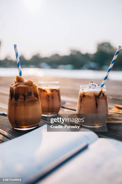 sommer, urlaub und eiskaffee am strand - coffee frappe stock-fotos und bilder