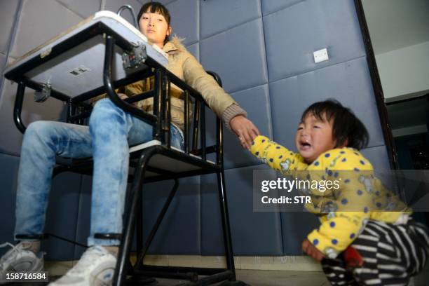 This picture taken on December 18, 2012 shows a mother holding her baby's hand in a police bureau, after she and her husband were both arrested for...