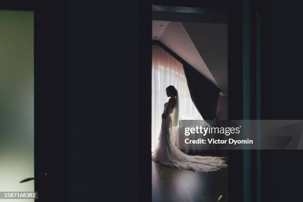 graceful young bride in her dark bedroom - wedding celebration stock pictures, royalty-free photos & images