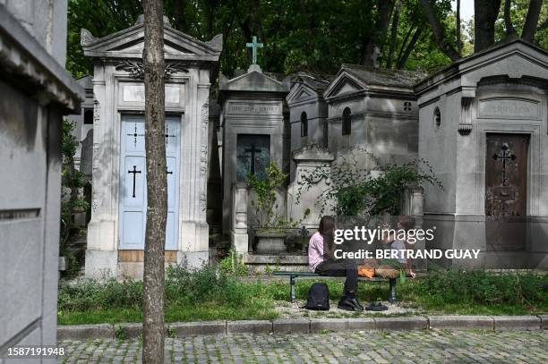 People sit on a bench at the Pere Lachaise cemetery in Paris, on August 8, 2023.