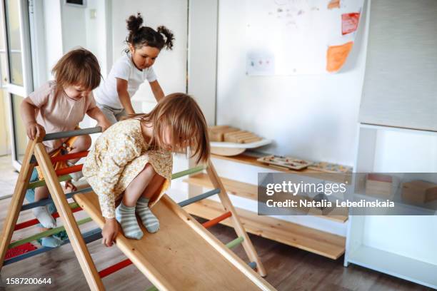 healthy play, sustainable future: heartwarming scene of three children participating in sports at eco-friendly wooden sports complex, nurturing physical well-being and encouraging environmental responsibility in kindergarten. - モンテッソーリ教育 ストックフォトと画像