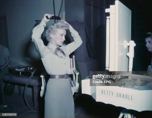 American actress Betty Grable fixes her hair before a performance, circa 1945.
