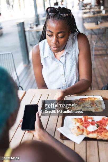 sending money via mobile phone - african american restaurant texting stockfoto's en -beelden