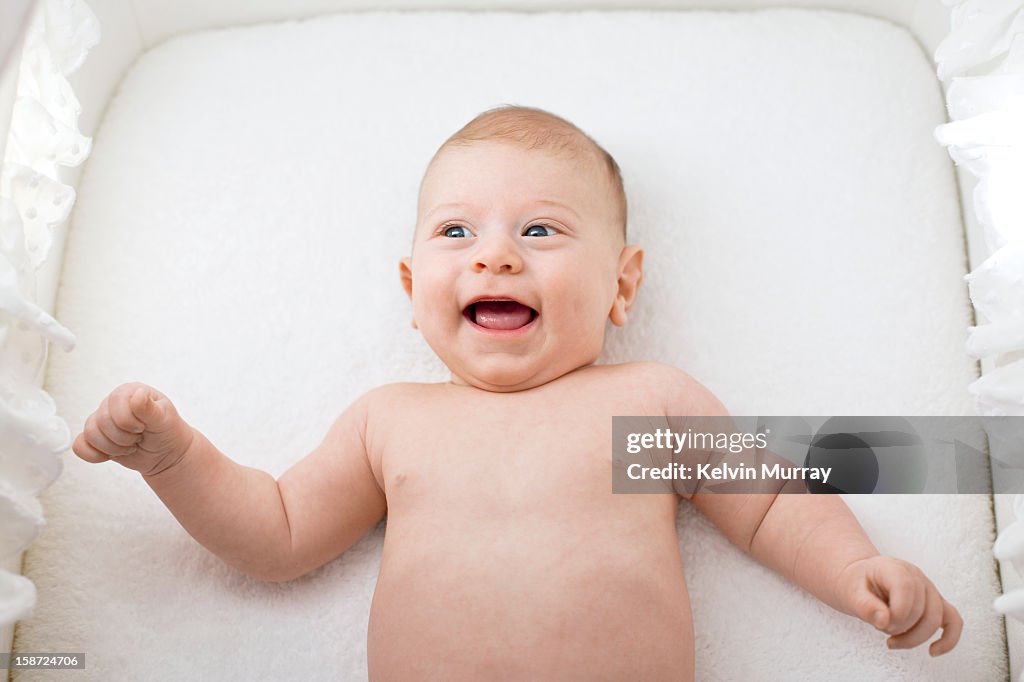 Baby smiling in cot