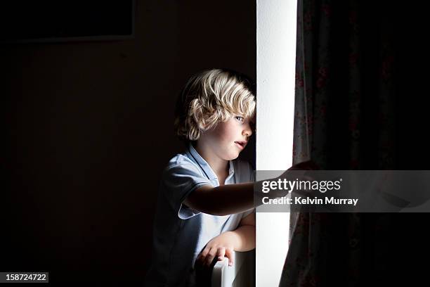 Boy peeks through window curtains